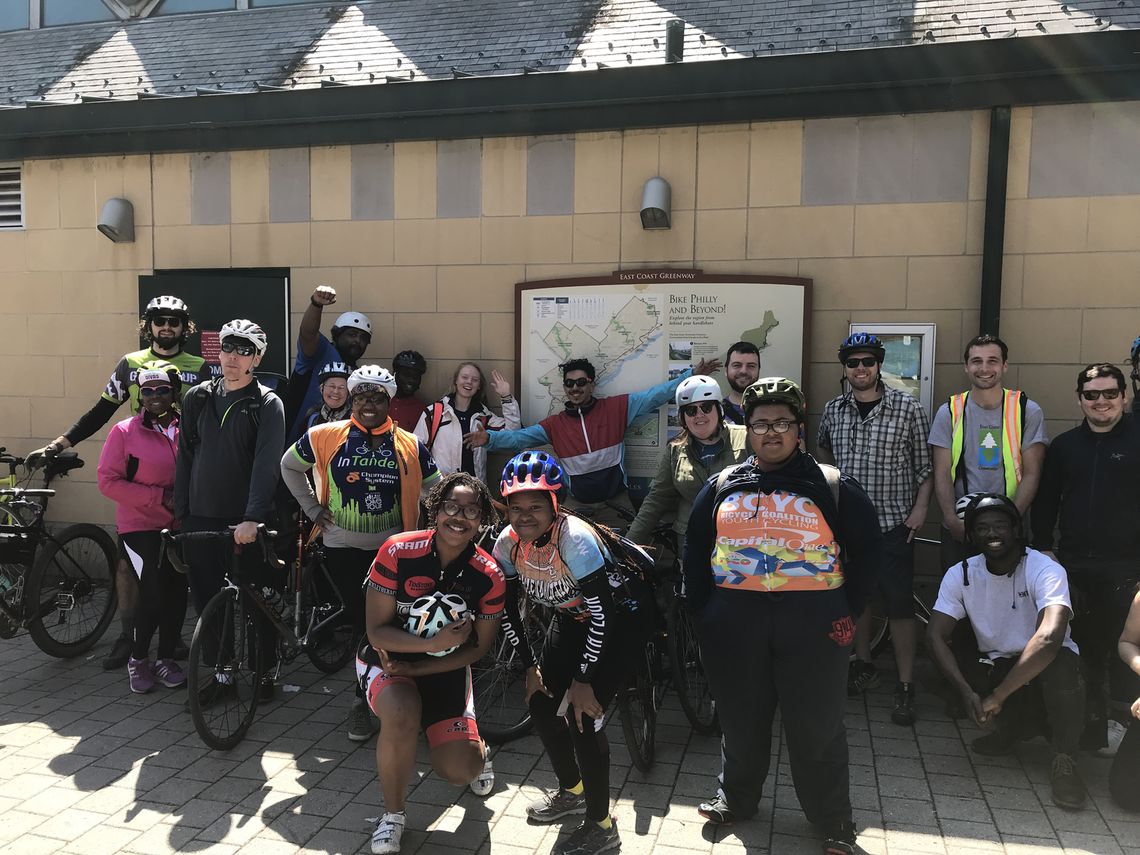 Youth Advisory Committee members of the Bicycle Coalition Youth Cycling Program led a bike tour on Saturday for Mid-Atlantic Summit attendees, leading them from the art museum steps to the program's new headquarters and back. They pose here by a sign about the East Coast Greenway on the Schuylkill River Trail.